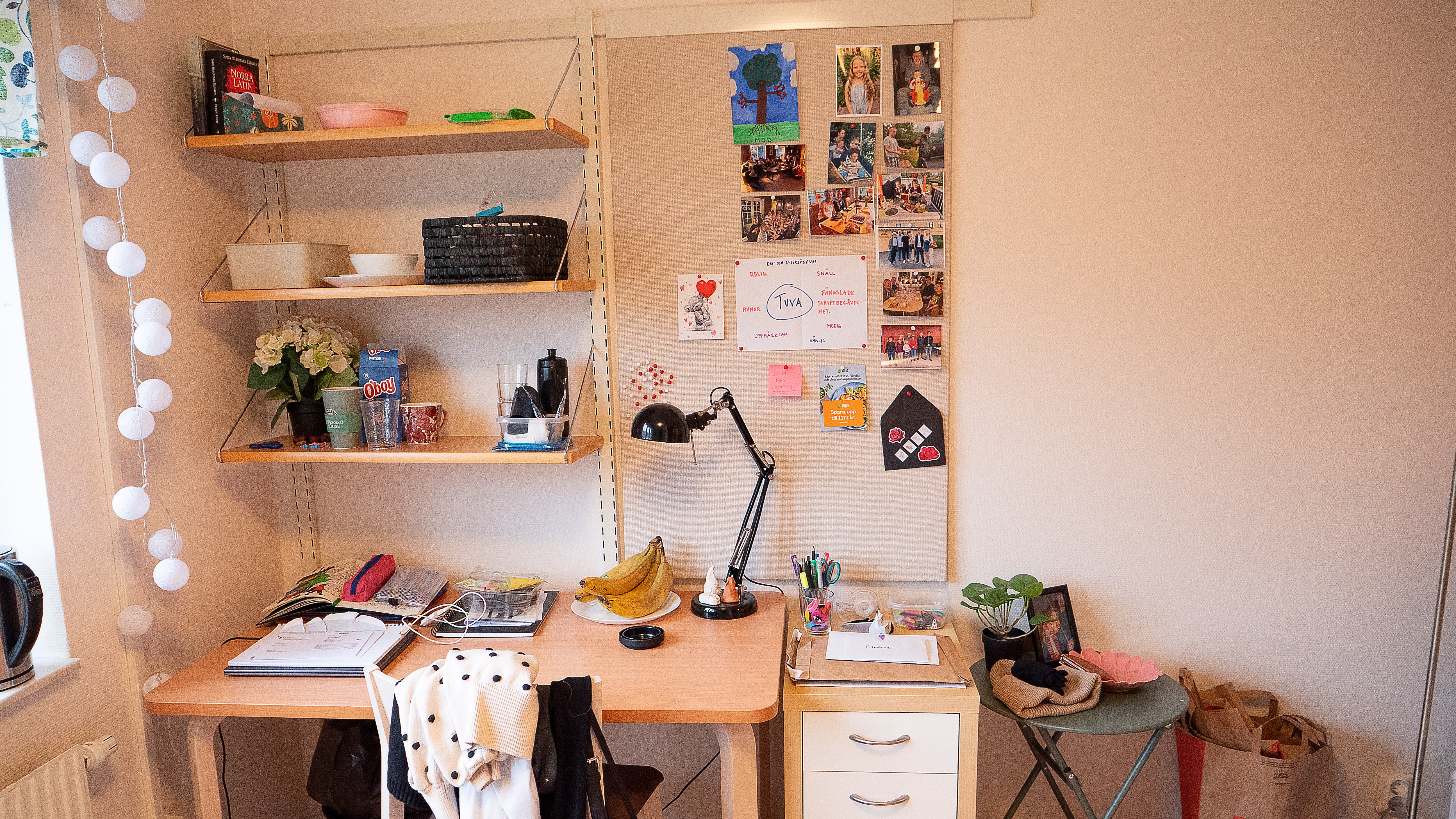 Skrivbord och hurts med hylla och anslagstavla ovanför.