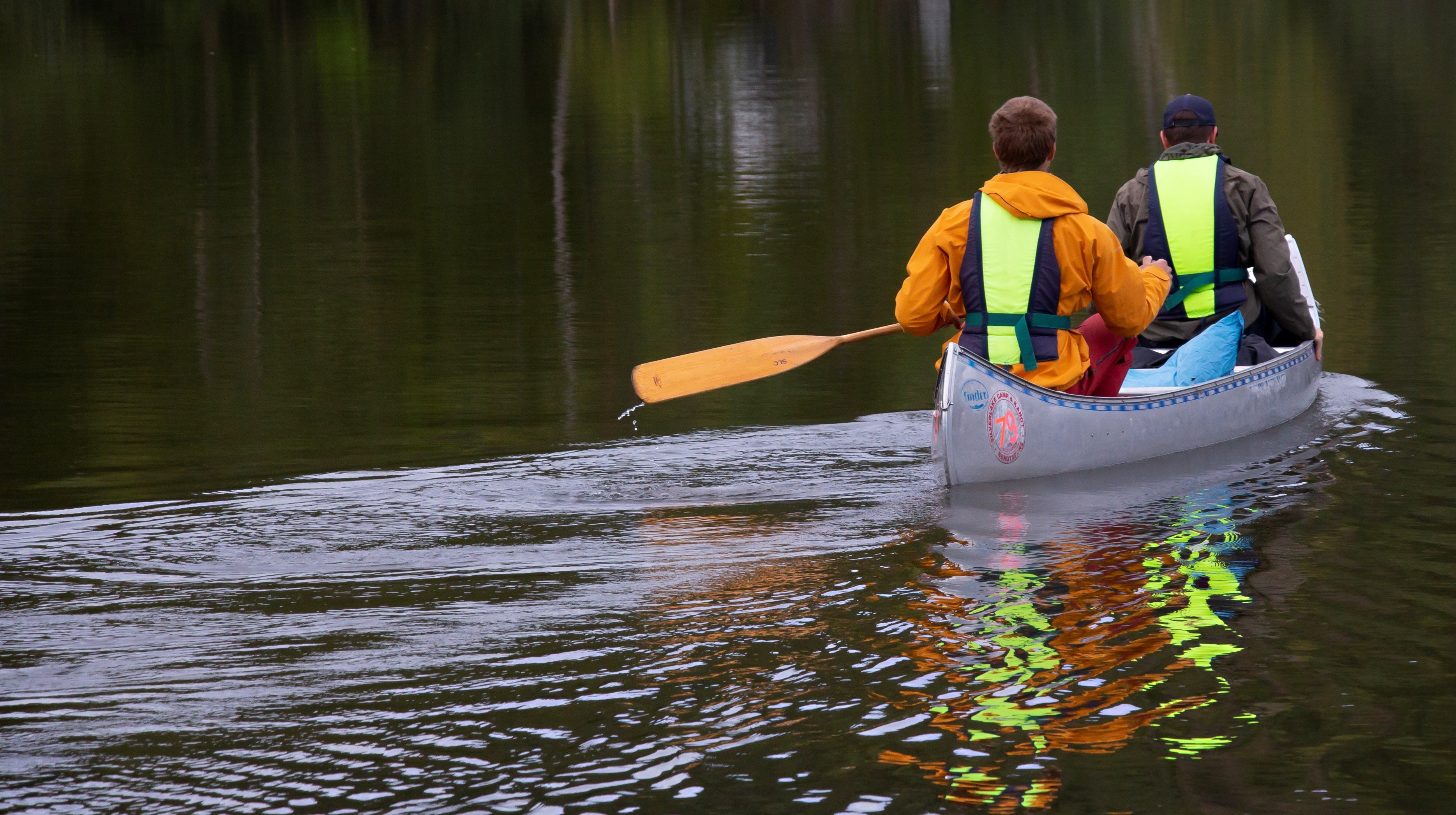 Två personer, fotograferade bakifrån, som paddlar iväg i en kanot.