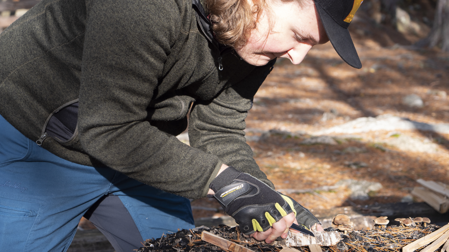 En deltagare förbereder en tändpinne för att kunna göra upp eld utomhus.