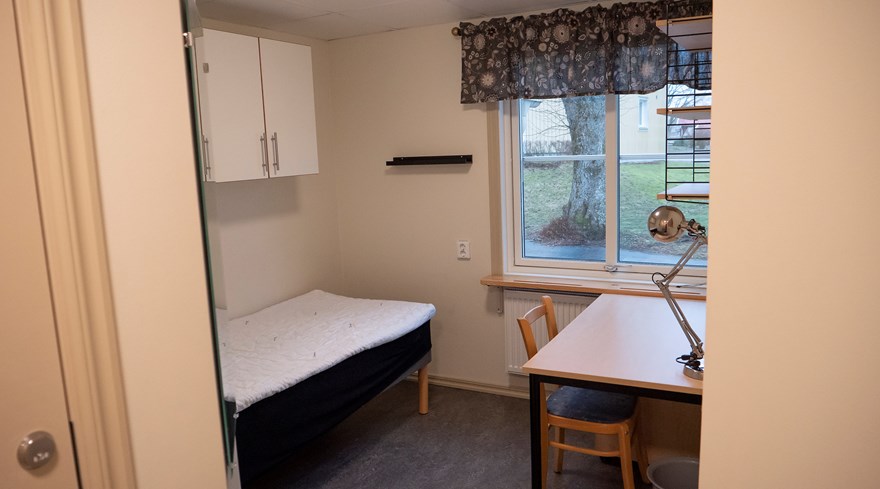Foto på litet internatrum, Gråbo, Dalslands folkhögskola. På bilden syns en säng med skåpp över och ett skrivbord framför ett fönster.