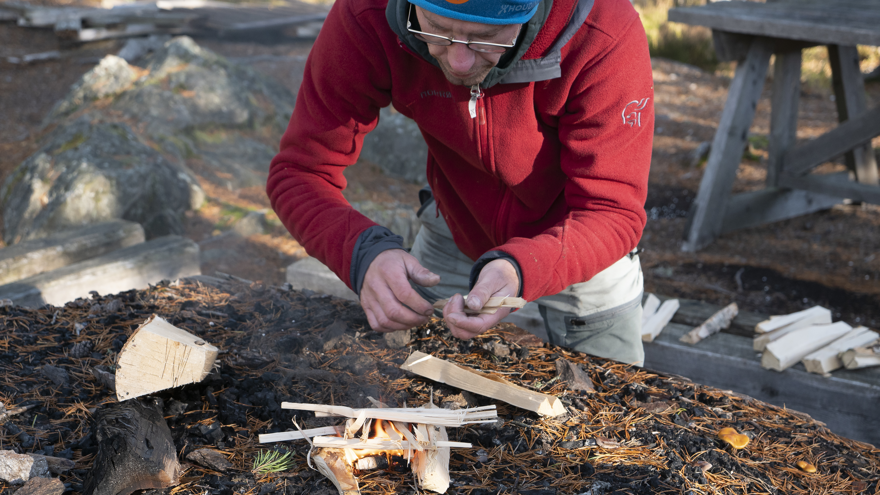 Läraren på Allmän kurs Friluftsliv gör upp en eld utomhus.