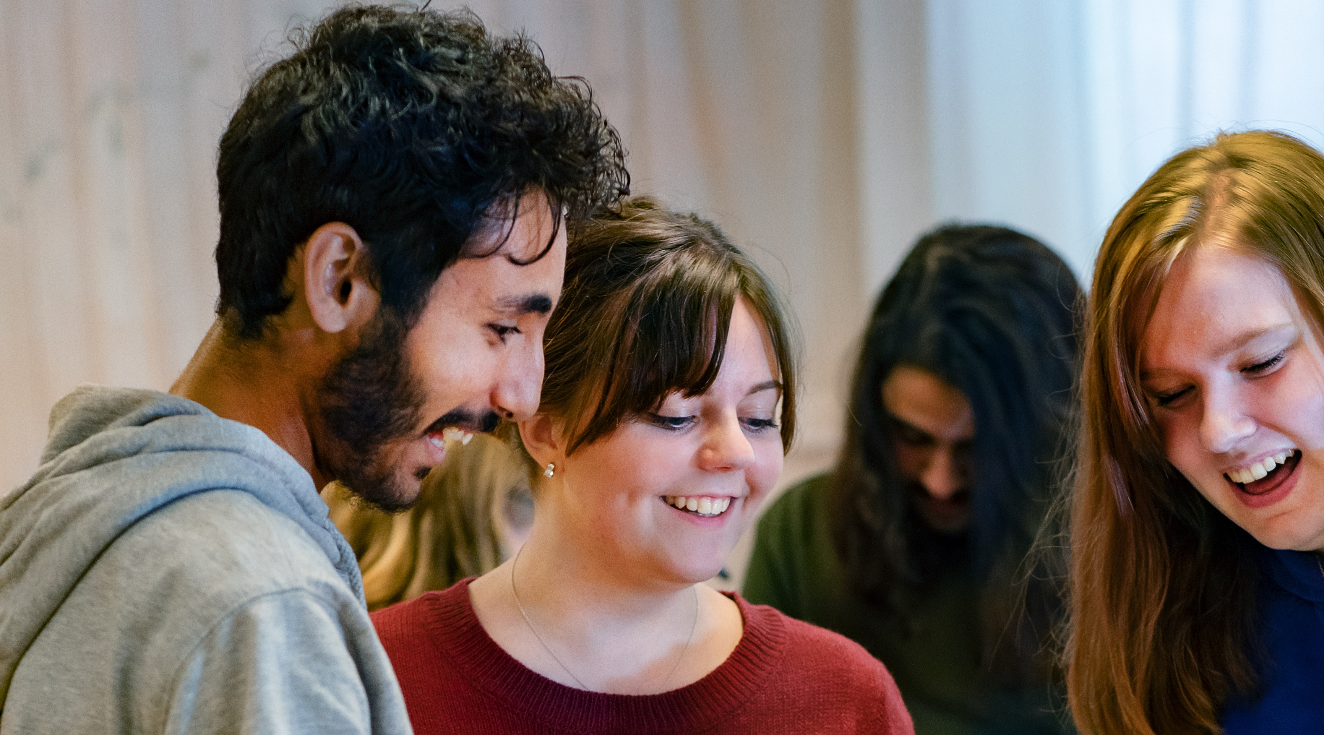 Tre personer som tittar nedåt och ler.