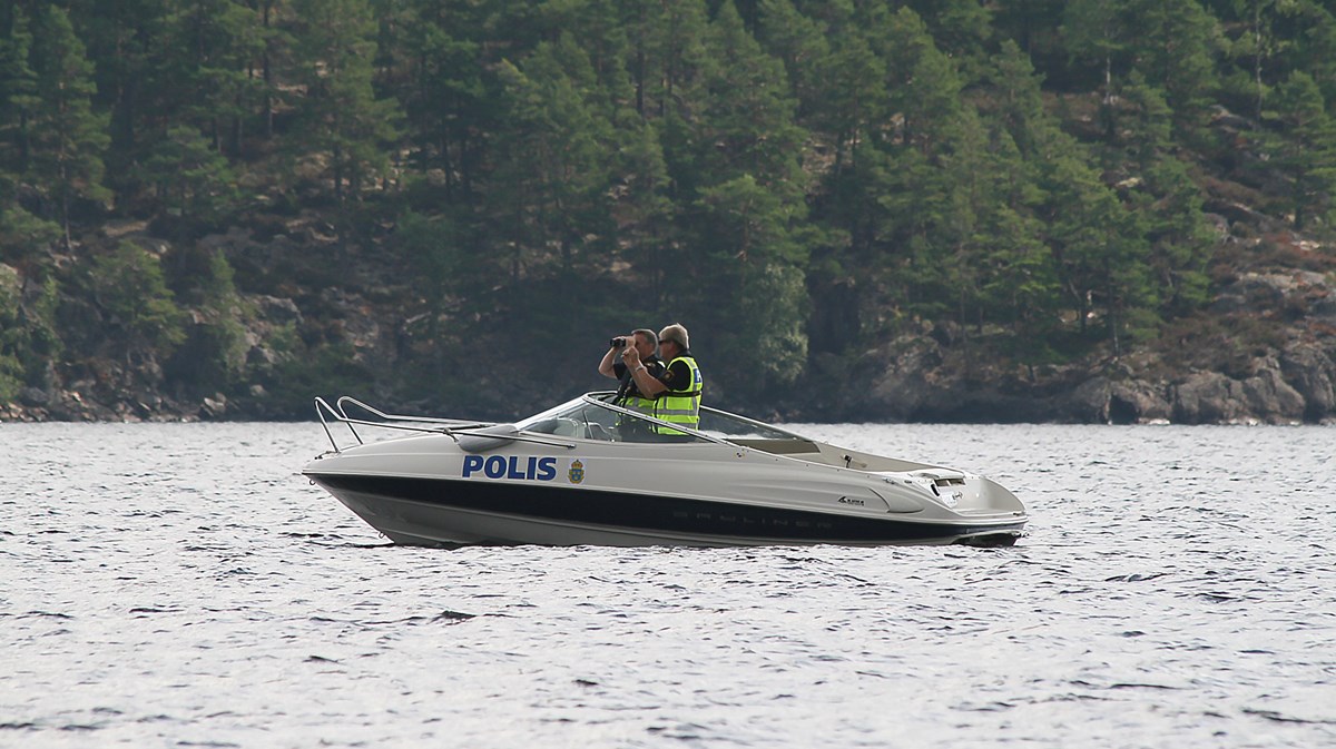 En polisbåt med två poliser som spanar.