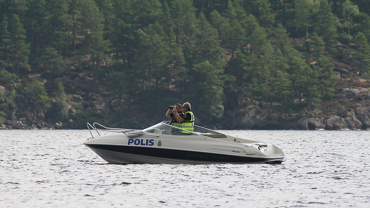 Två poliser som spanar i en polisbåt