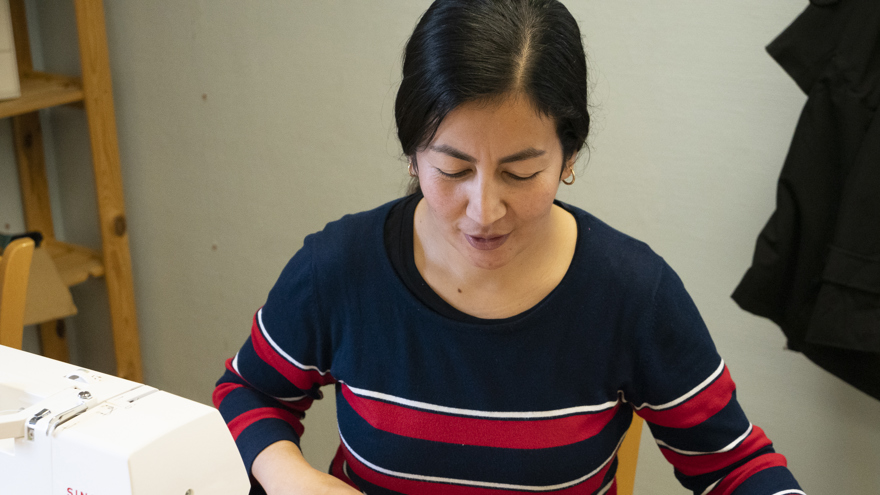 En deltagare som sträcker ut ett förkläde vid en symaskin.