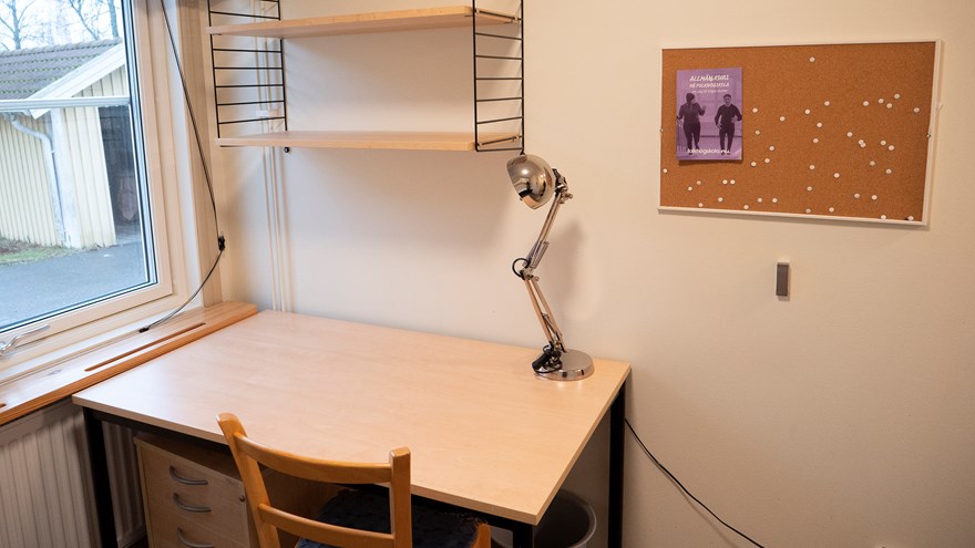 Litet enkelrum, Gråbo, Dalslands folkhögskola i Färgelanda. Ett skrivbord och stol med en hylla ovanför.