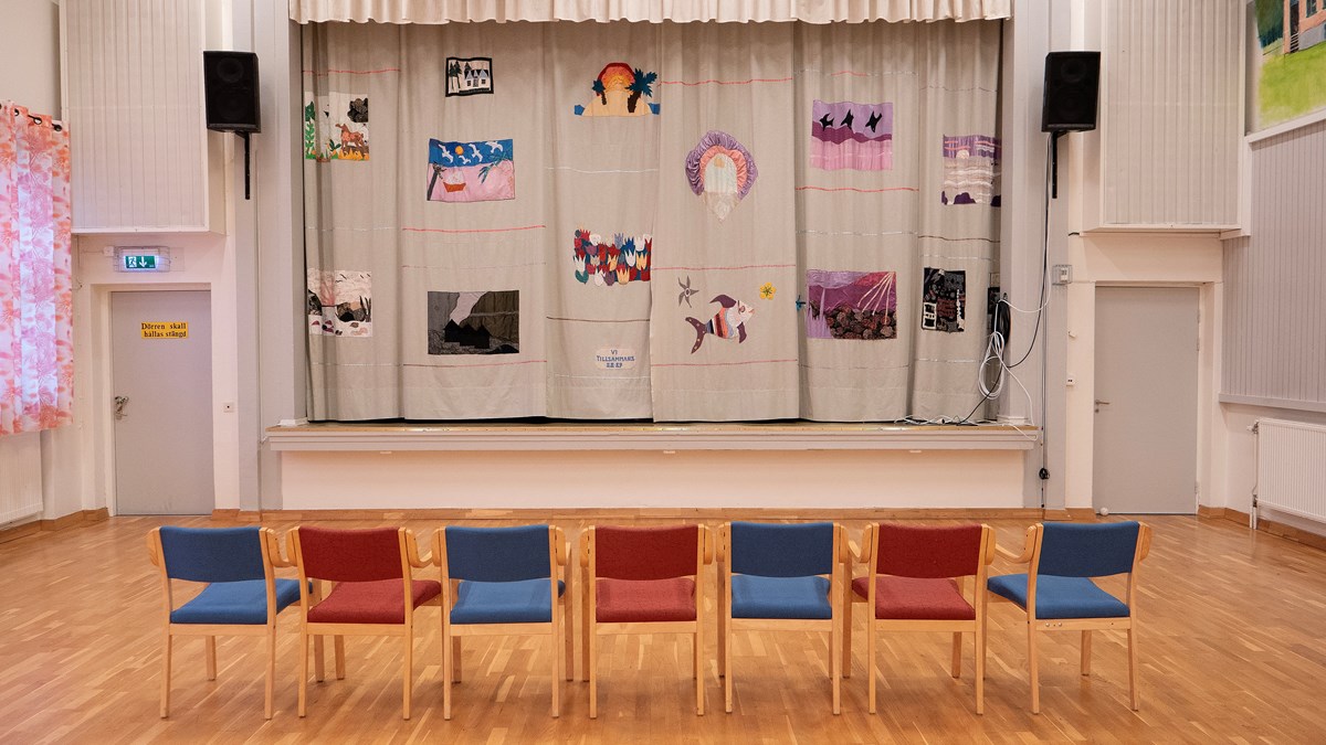 Stora salen på Dalslands folkhögskola i Färgelanda. Sju stolar står uppställda framför en scen.