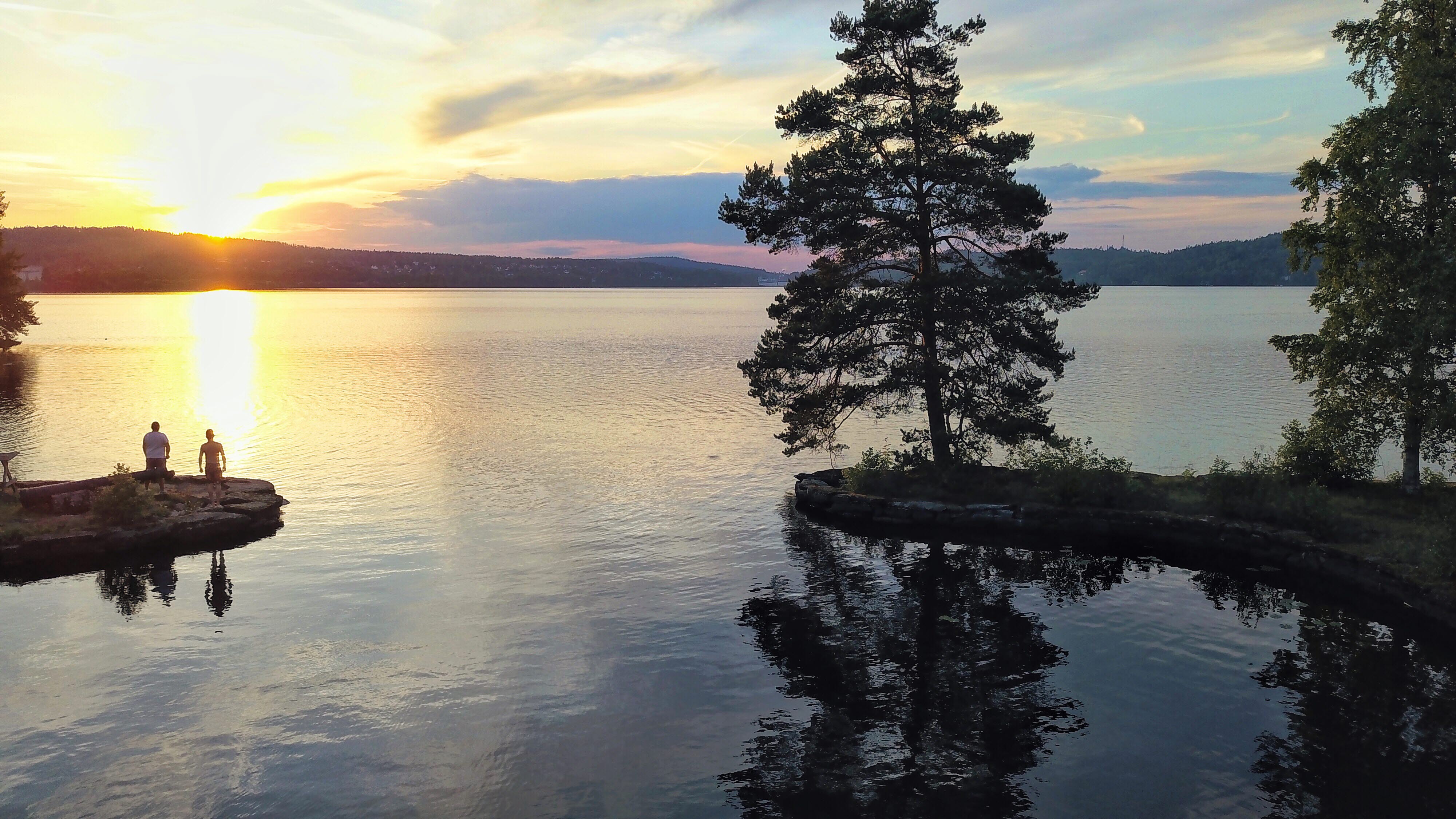 Två personer vid en sjö i Dalsland i solnedgången.