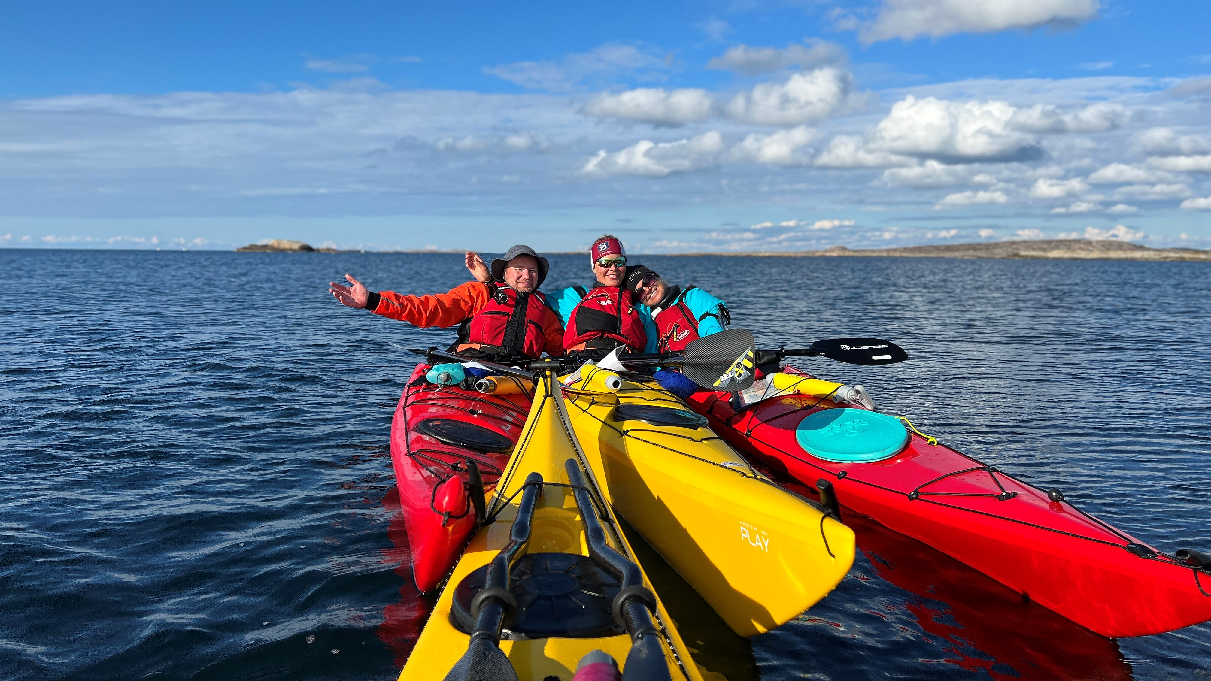 Tre personer i havskajaker.