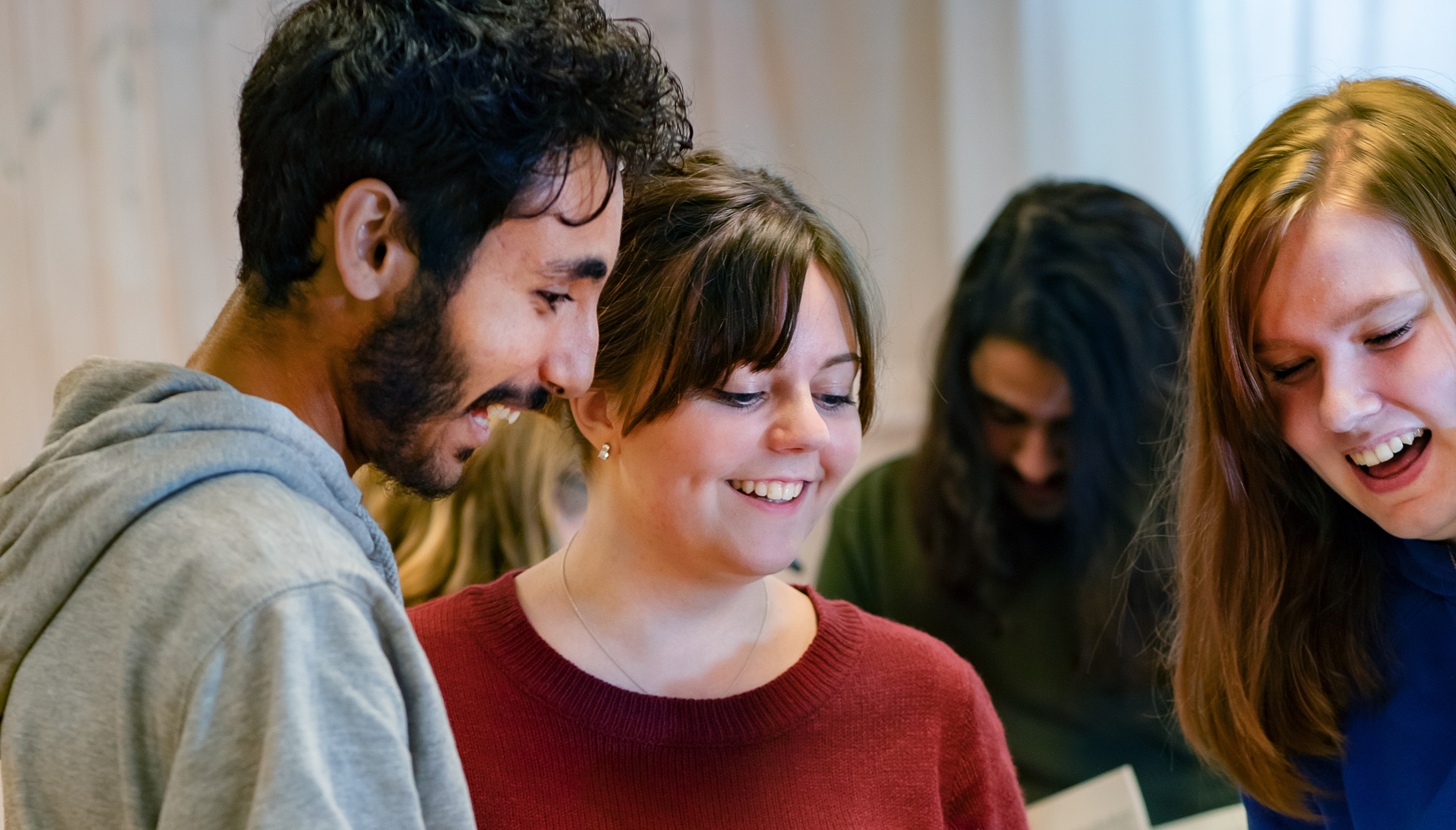 Tre personer som tittar nedåt och ler.