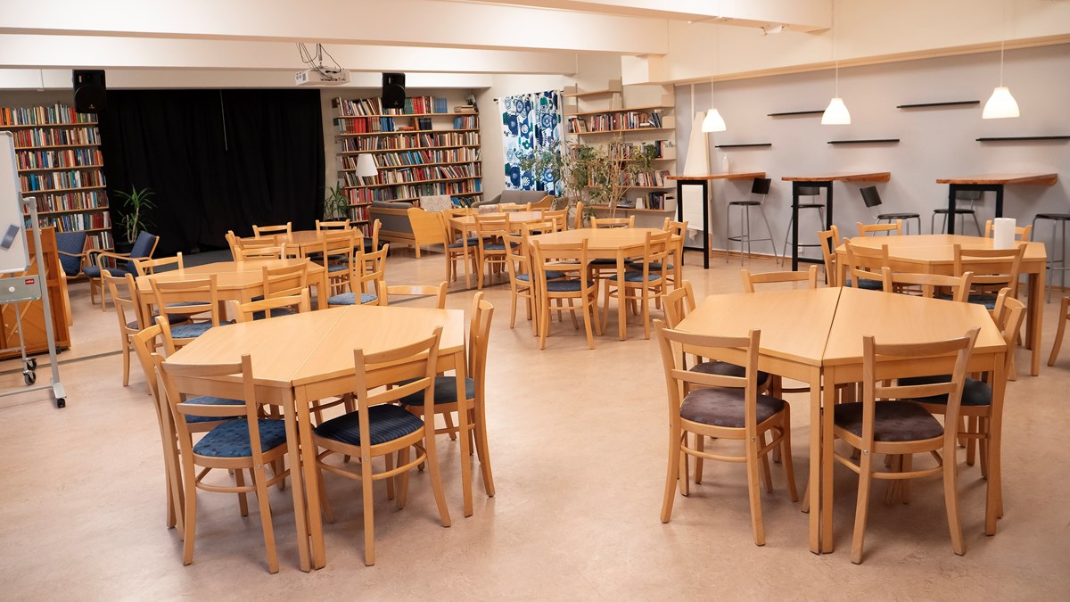 Bibliofiket på Dalslands folkhögskola i Färgelanda. Här syns ett antal bordsgrupper framför en scen. På båda sidor om scenen syns hyllor med böcker från golv till tak.