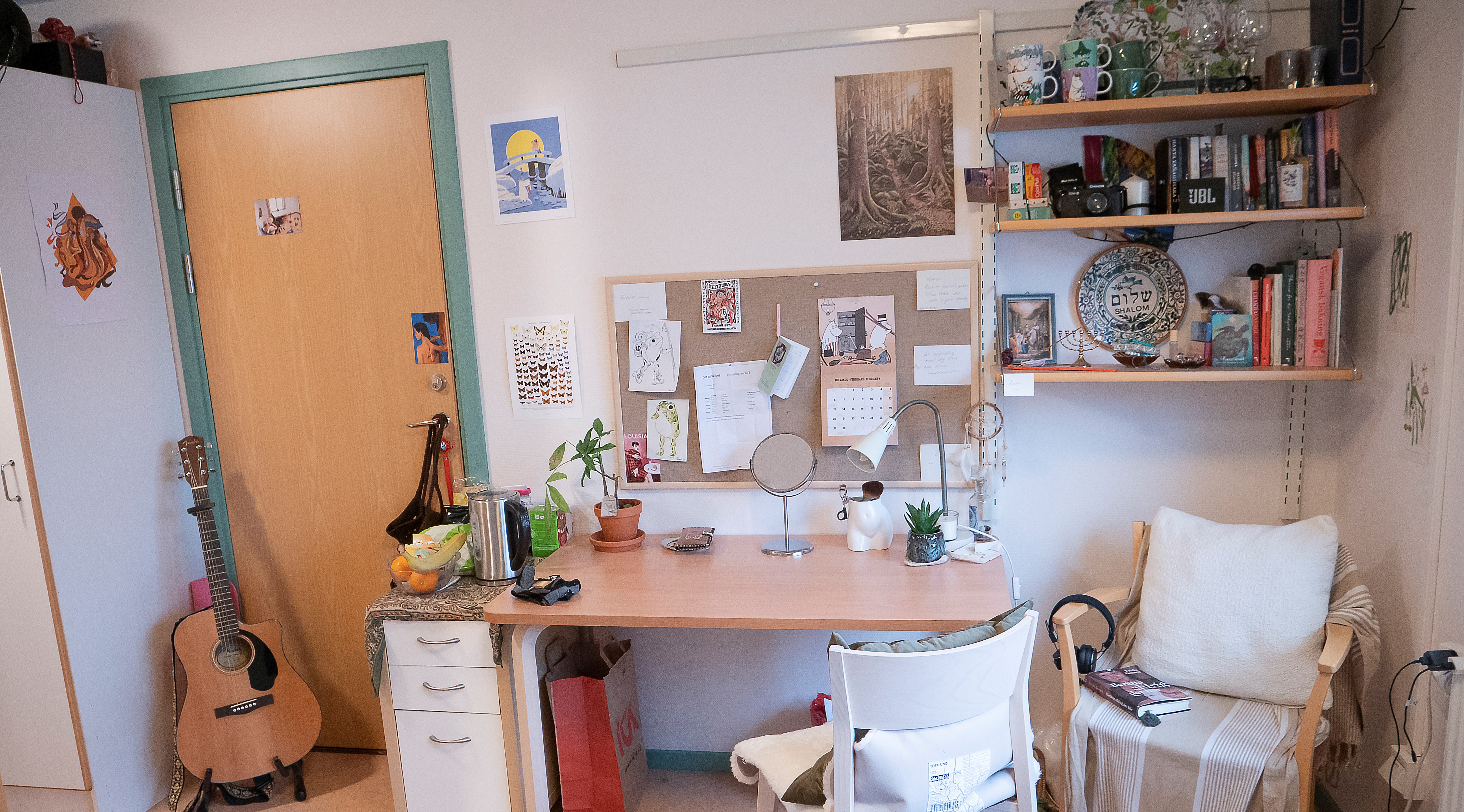 Skrivbord med hurts, fåtölj, stol och en gitarr.