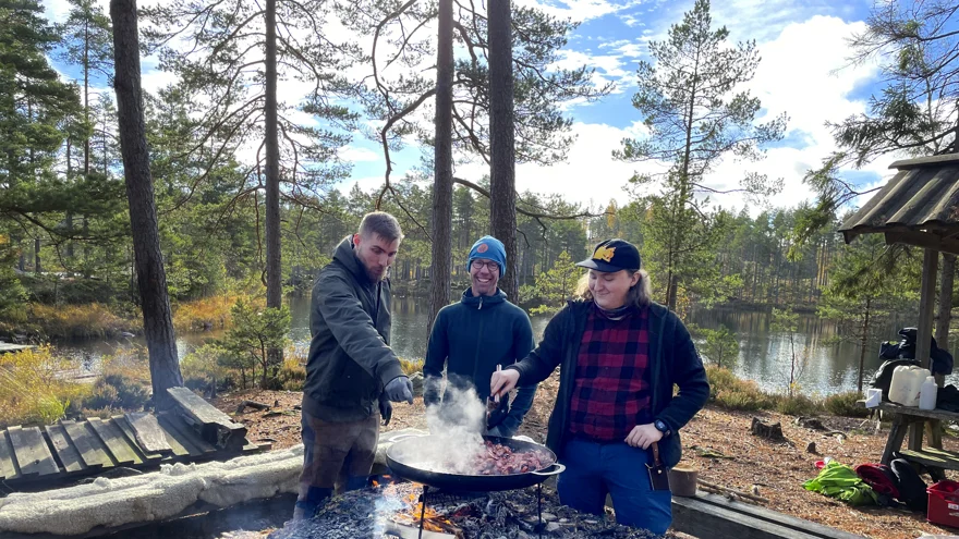 Tre personer lagar mat på en stekhäll