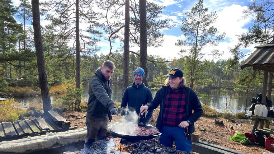Tre personer lagar mat på en stekhäll