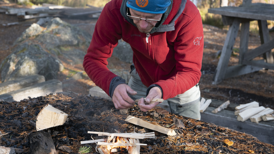 Läraren på Allmän kurs Friluftsliv gör upp en eld utomhus.