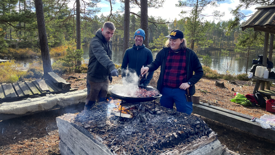 Tre personer lagar mat på en stekhäll