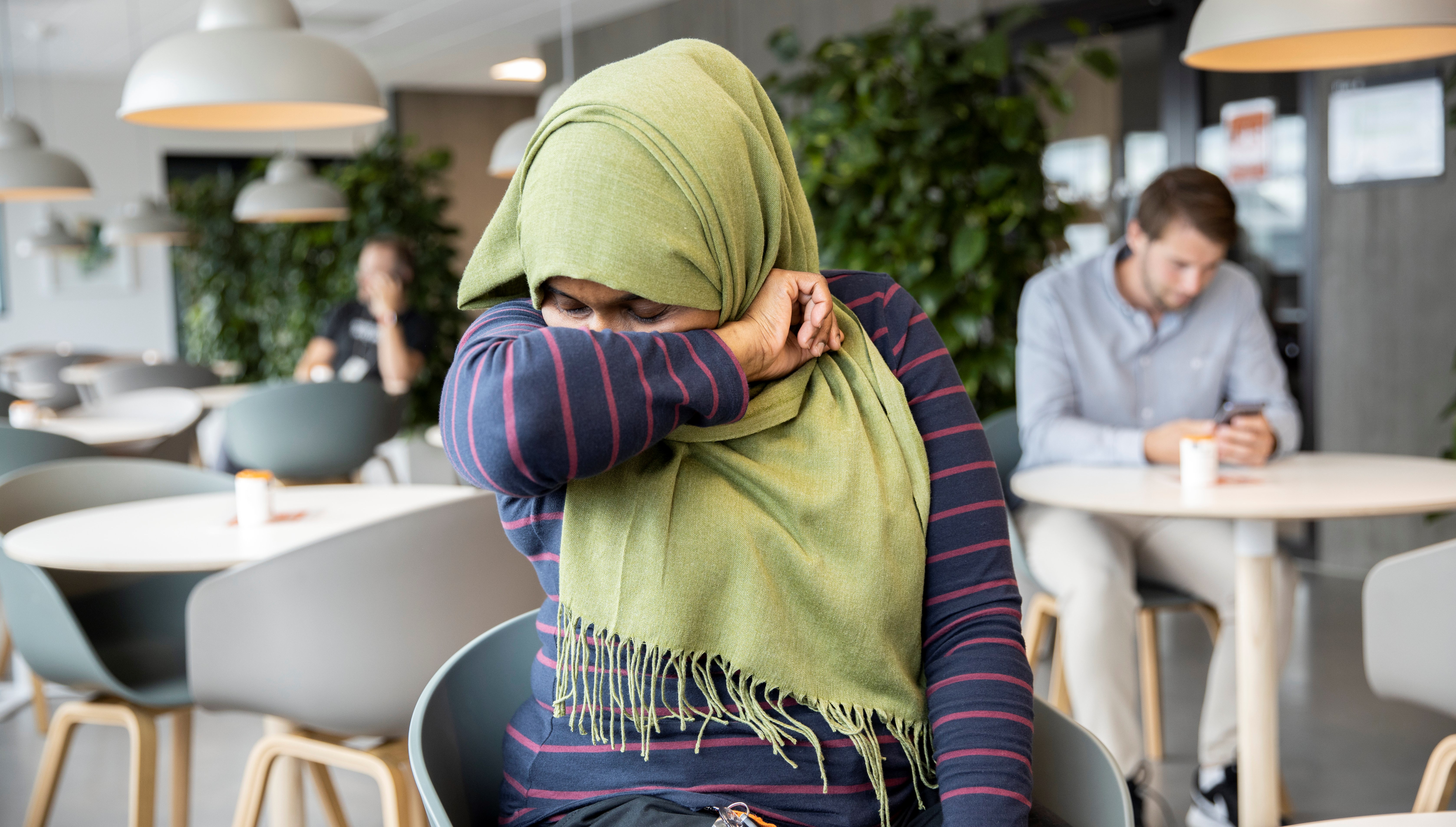 En person som hostar i armvecket.