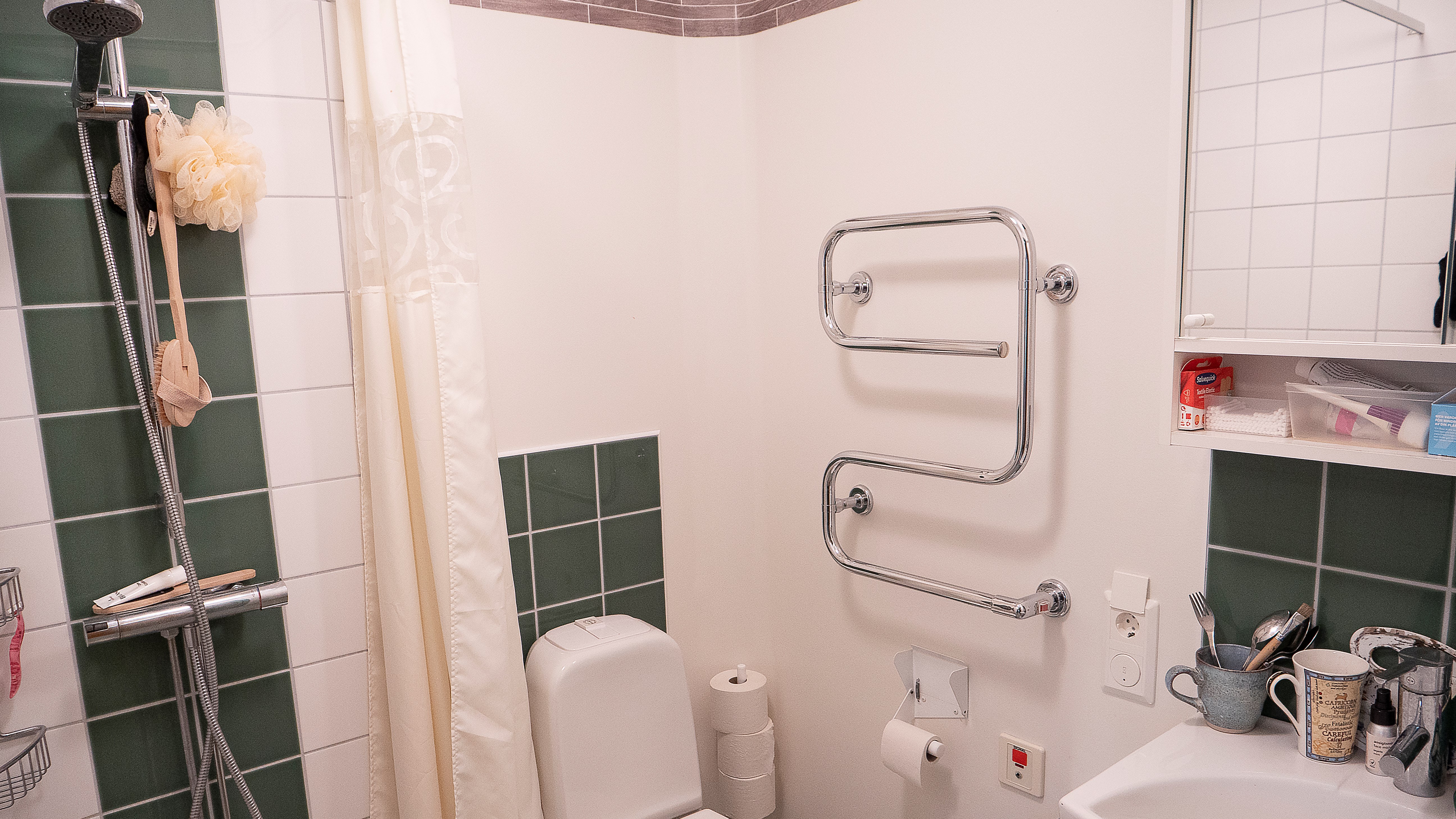 Badrum med dusch, toalettstol, handfat och badrumsspegel, Nybo.