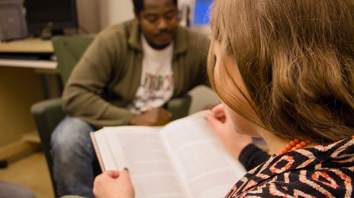 En folkhögskoledeltagare som läser i en bok. I bakgrunden syns en annan folkhögskoledeltagare.