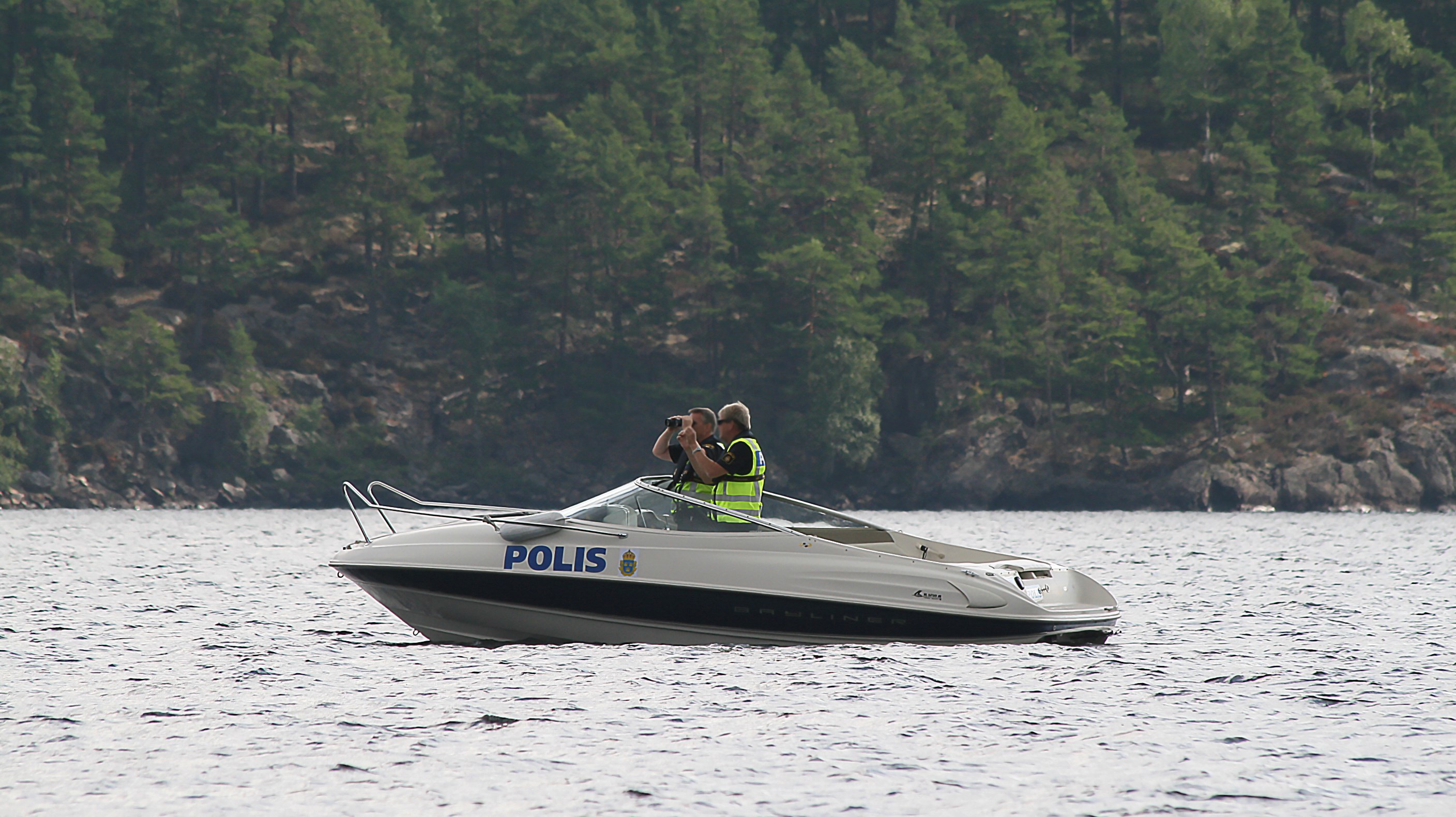 Två poliser som spanar i en polisbåt