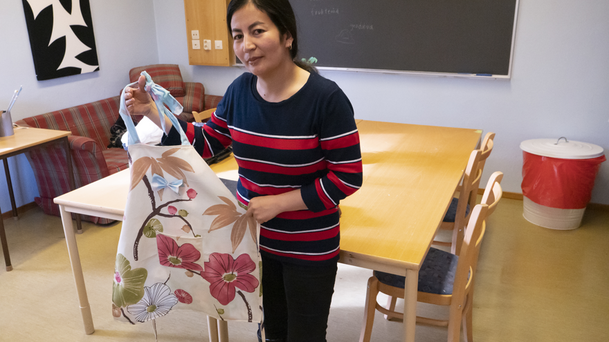 En folkhögskoledeltagare visar upp ett förkläde, som är skapat av en gammal gardin.