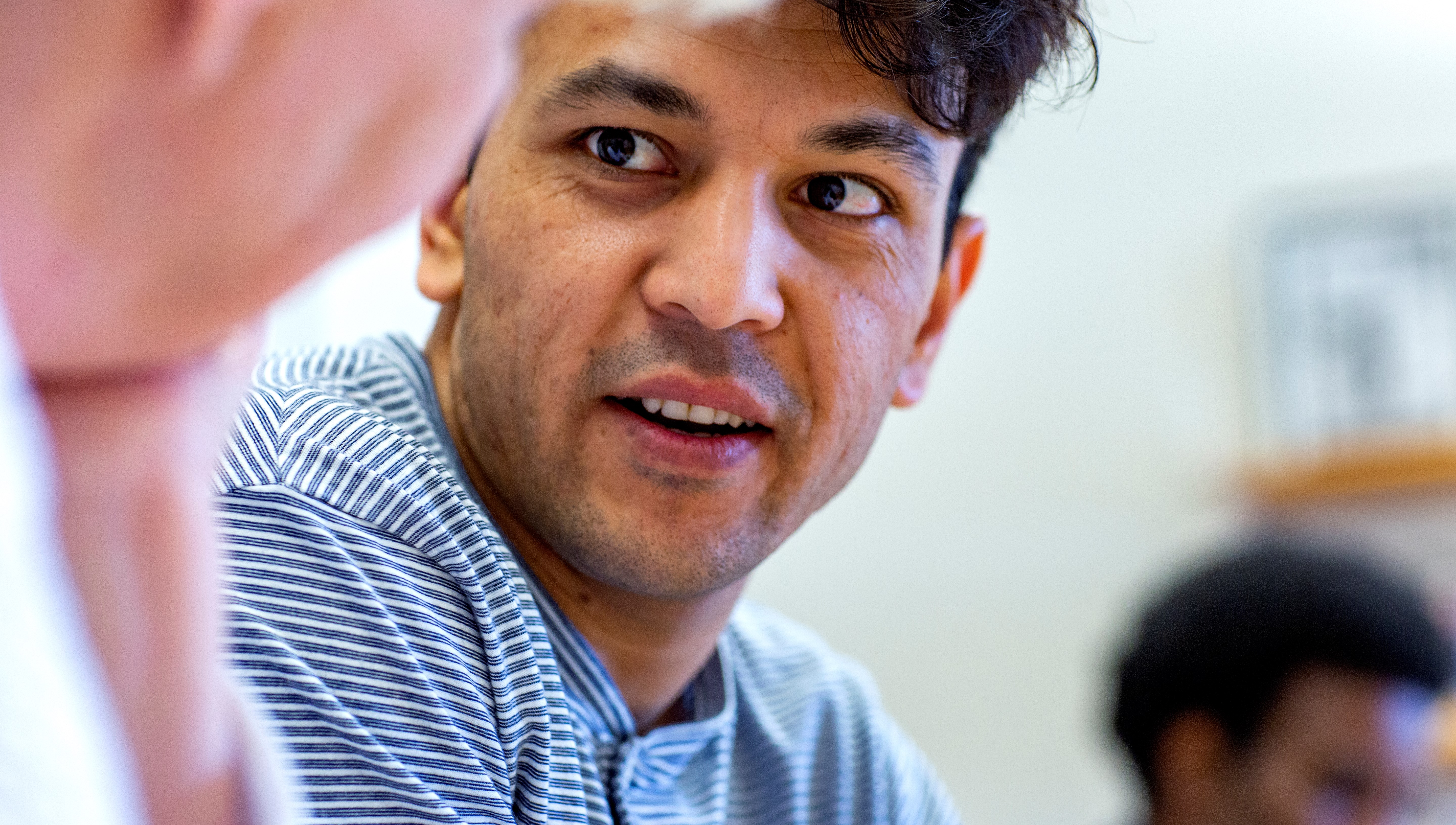 En närbild på en folkhögskoledeltagare i ett klassrum. Personen ser ut att lyssna på en annan person bredvid honom.