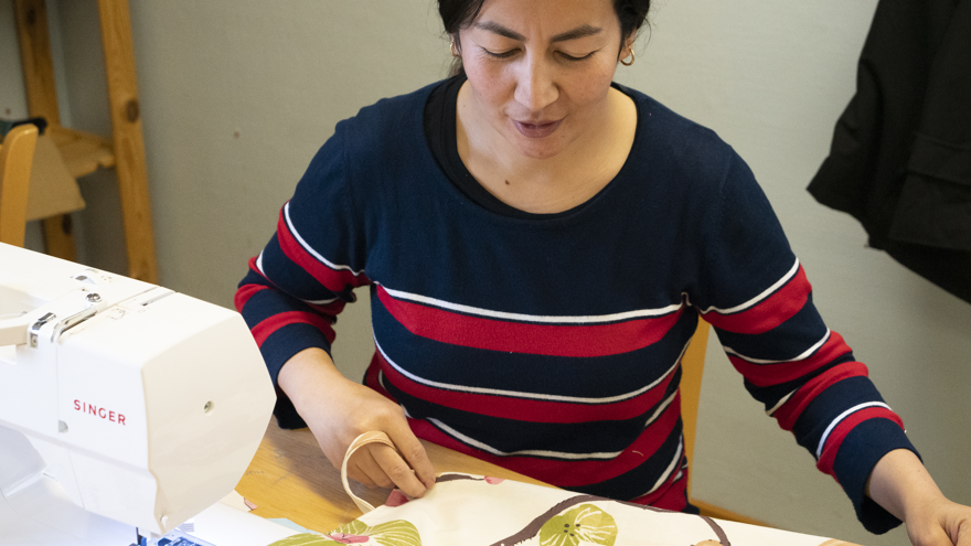 En deltagare som sträcker ut ett förkläde vid en symaskin.