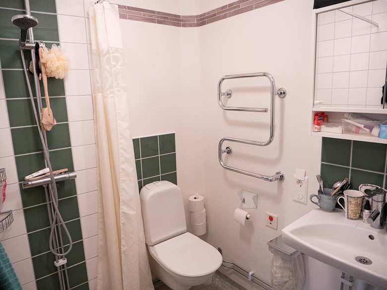 Badrum med dusch, toalettstol, handfat och badrumsspegel, Nybo.